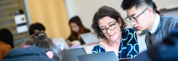 professor and student reviewing page on laptop